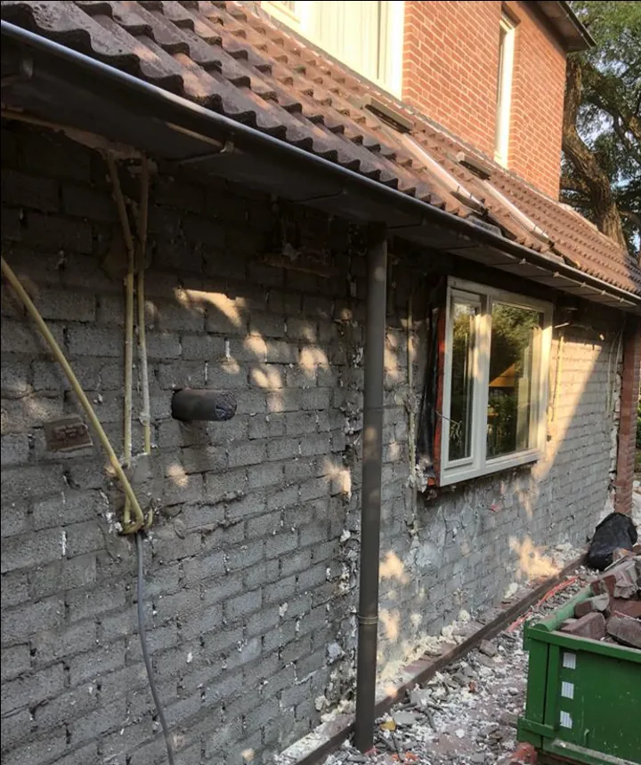 Voor: kale gevel met oud metselwerk en bouwpuin