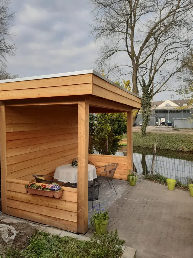 Houten overkapping met zithoek in de tuin